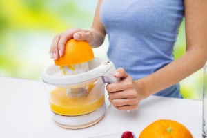 close up of woman squeezing orange juice at home
